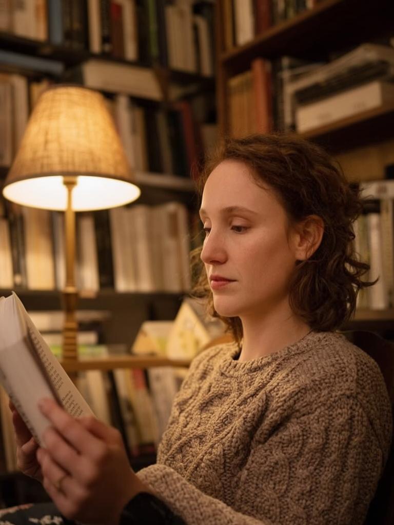 reading a book in a cozy library, warm lamplight