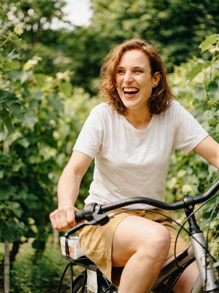laughing while riding a bicycle through a sunny vineyard