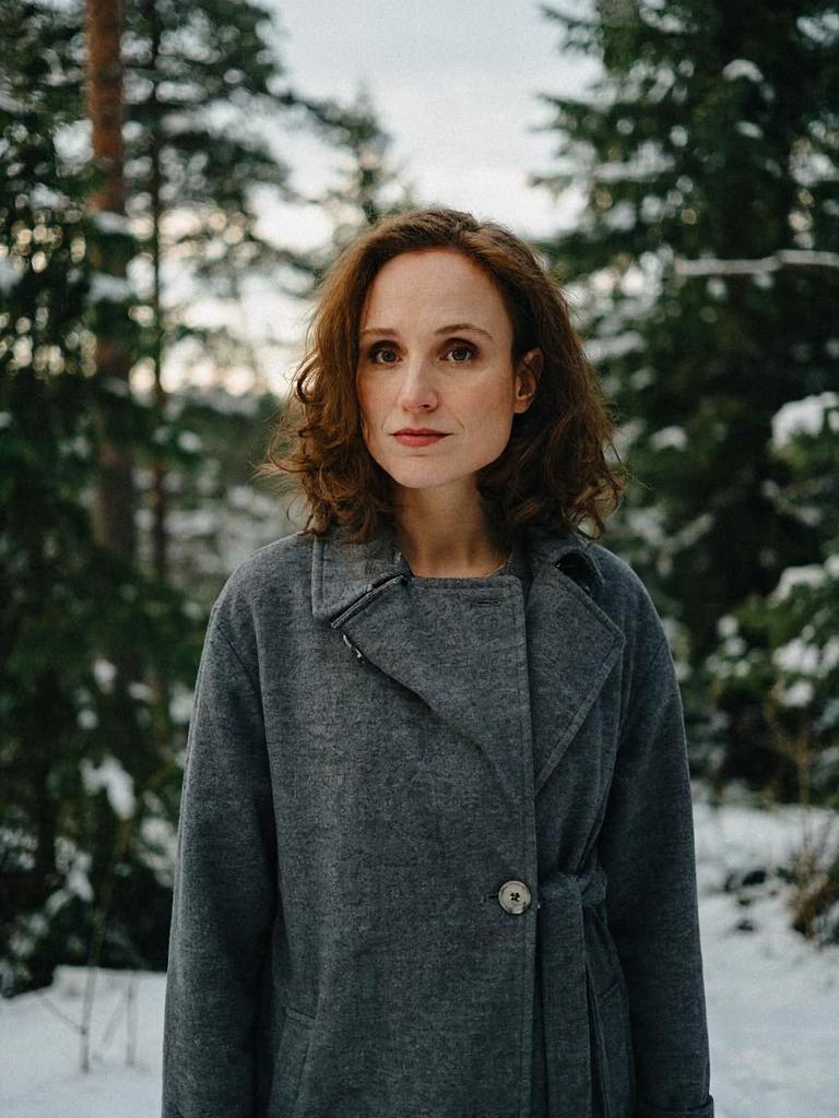 with a serious expression wearing a wool overcoat