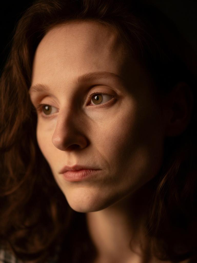 close-up portrait, contemplative, dramatic Rembrandt lighting, dark background